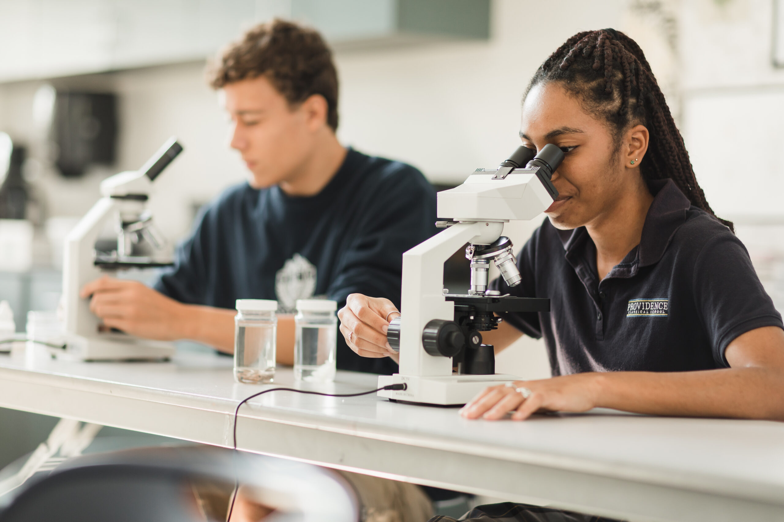 Ecology students at Providence Classical School in Spring, TX look through microscopes at specimens collected from the school pond.